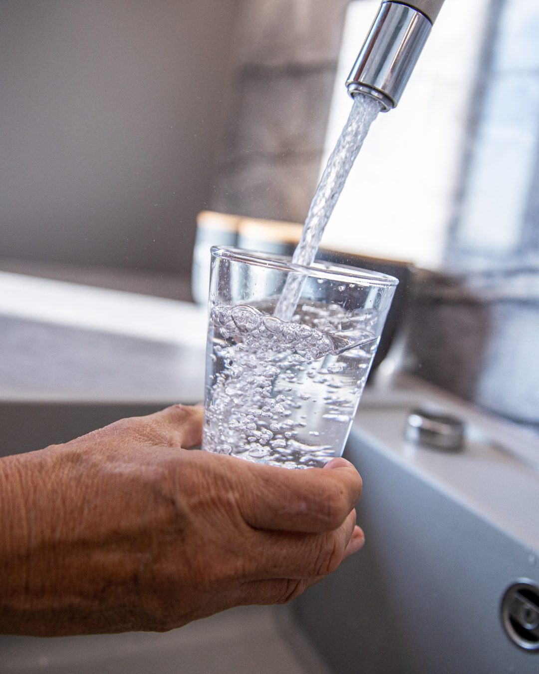 Clean filtered drinking water poured from kitchen faucet after professional installation.